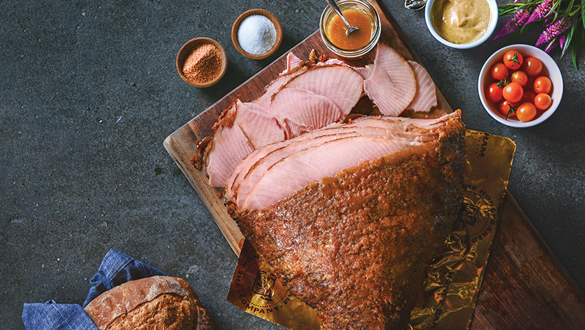 HoneyBaked sliced ham on wooden cutting board on table.