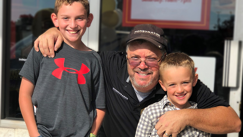 Male franchisee with two children in front of store-front