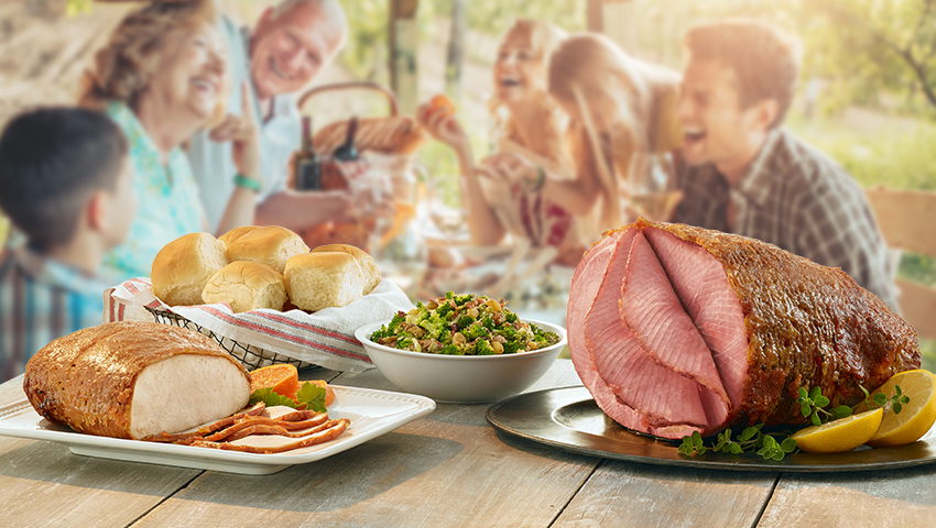 HoneyBaked sliced ham, sliced turkey, dinner rolls and side at outside catering table