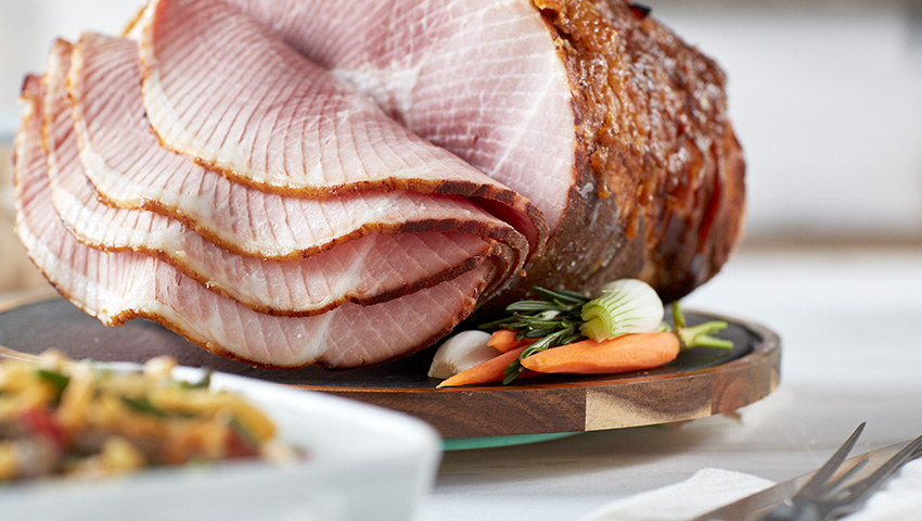 A mouthwatering Honey Baked Ham with spiral slices on full display.