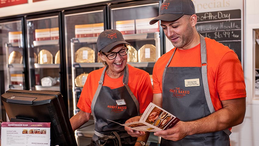 HoneyBaked employees looking at brochure.