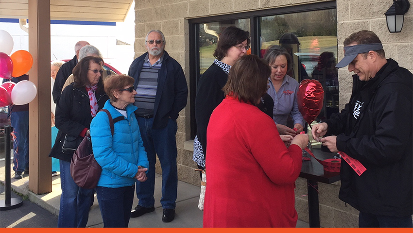 People gathered around in front of a Honeybaked restaurant.