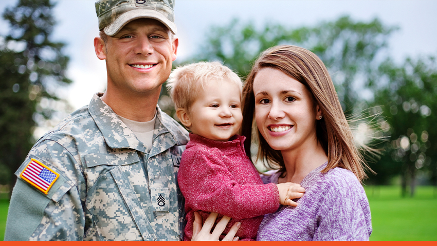 Army officer with his wife and child smiling in a group picture