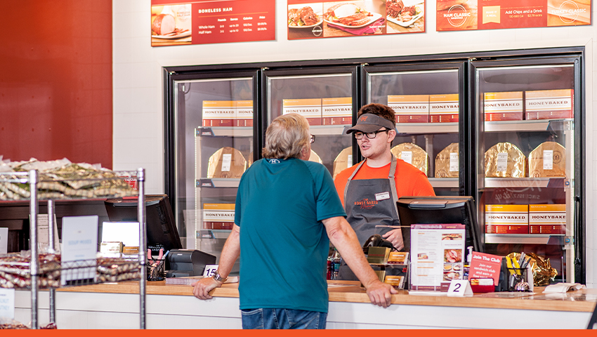 Image of a customer at HoneyBaked talking to an employee across the counter