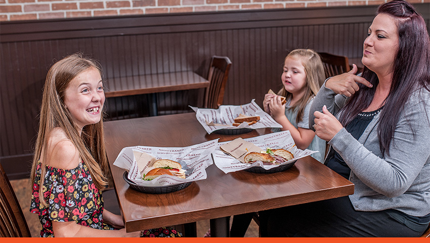 Image of family eating sandwiches at HoneyBaked