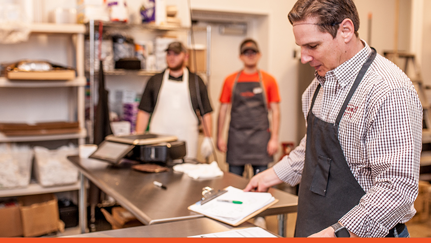 Image of three men in aprons working in kitchen