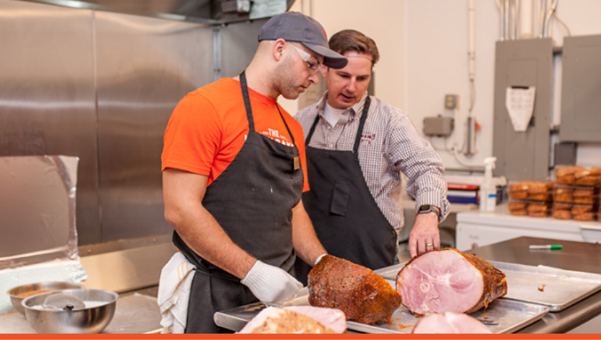 Image of two men in a kitchen with ham